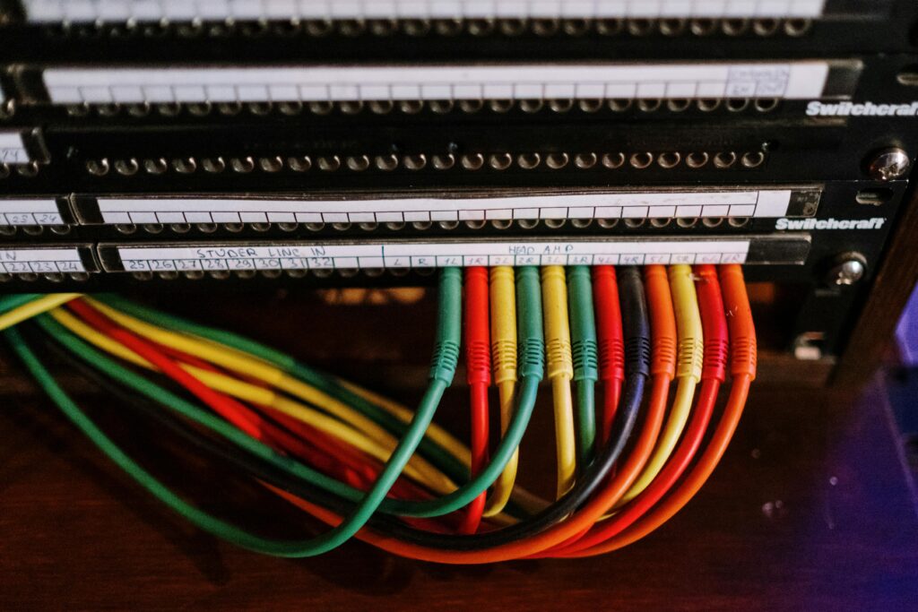 Close-up of colorful patch cables connected to a network panel with labels, indoors.
