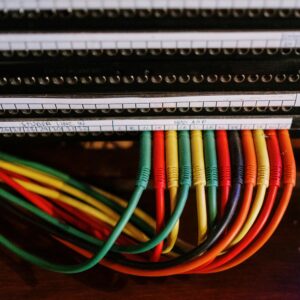 Close-up of colorful patch cables connected to a network panel with labels, indoors.
